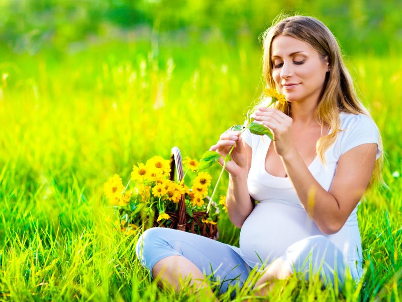 Pregnant woman sitting on green field