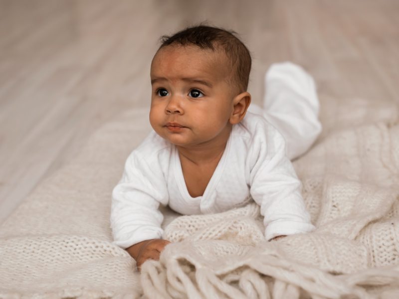 Thoughtful biracial mix of Hispanic and African American infant lying